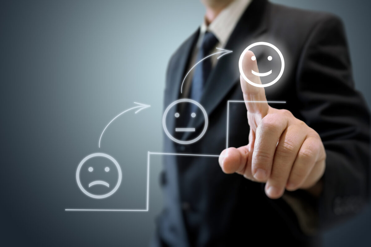 Image of a business customer pressing a smiling face icon, indicating customer satisfaction.