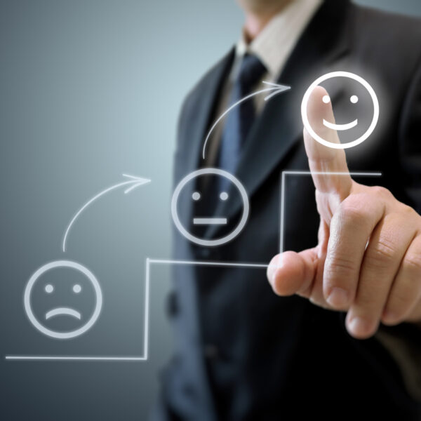 Image of a business customer pressing a smiling face icon, indicating customer satisfaction.