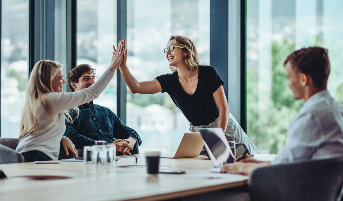 Representatives from two B2B companies high-five after executing a successful brand collaboration.