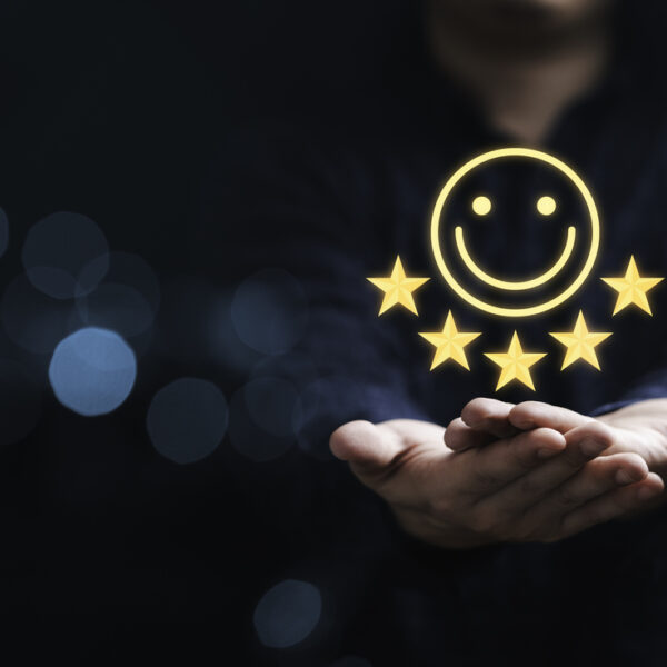 Hands holding a superimposed 5-star symbol and happy face indicating customer satisfaction.