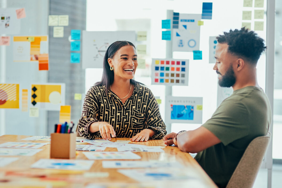 Two colleagues smile as they work together on their company’s B2B content marketing strategy.