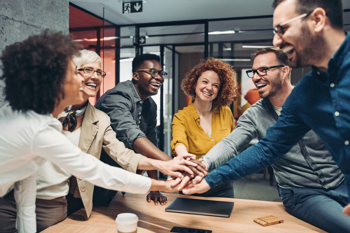 Marketing team puts their hands in together after collaborating on a B2B brand equity initiative.